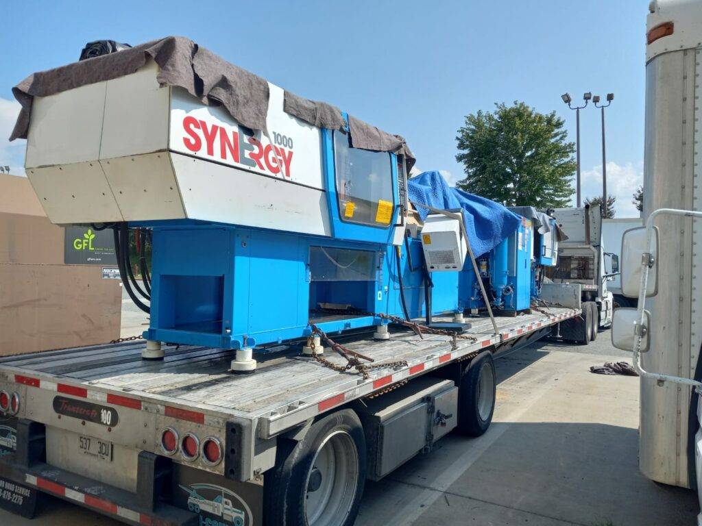 CNC machine loaded on a flatbed trailer for transportation.