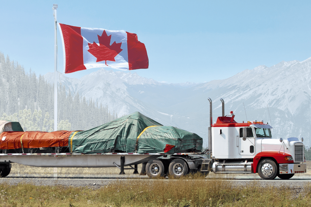 Flatbed truck carrying a full truckload (FTL) of CNC machinery from Canada to the USA