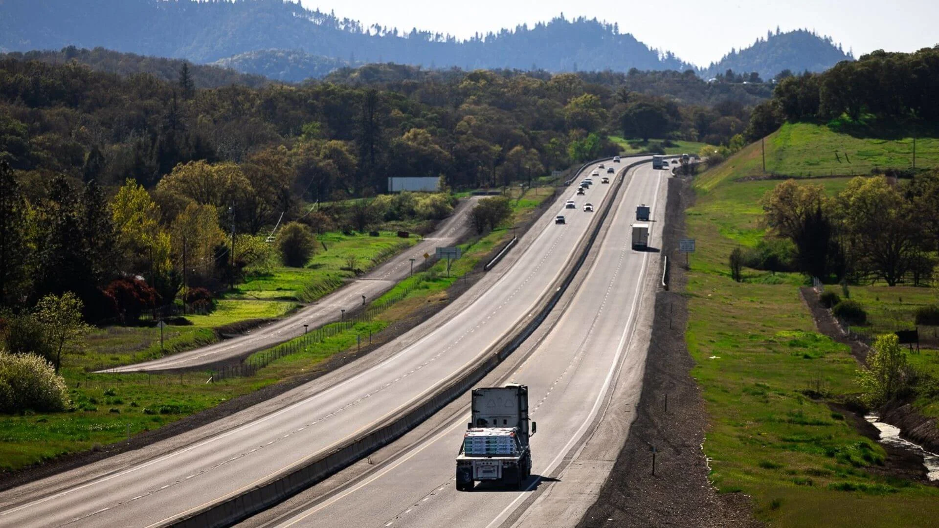 Flatbed truck traveling an Oregon highway through forested mountain terrain