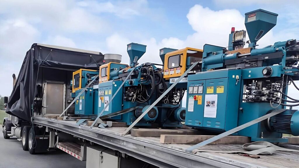 BOY injection molding machine secured on a Conestoga flatbed trailer for transport by Abound Transport.