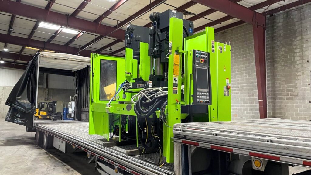 Green injection molding machine Conestoga stepdeck transport