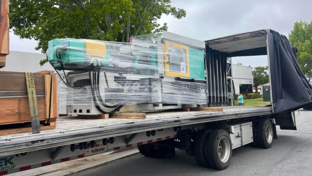 Injection molding machine loaded inside Conestoga flatbed trailer