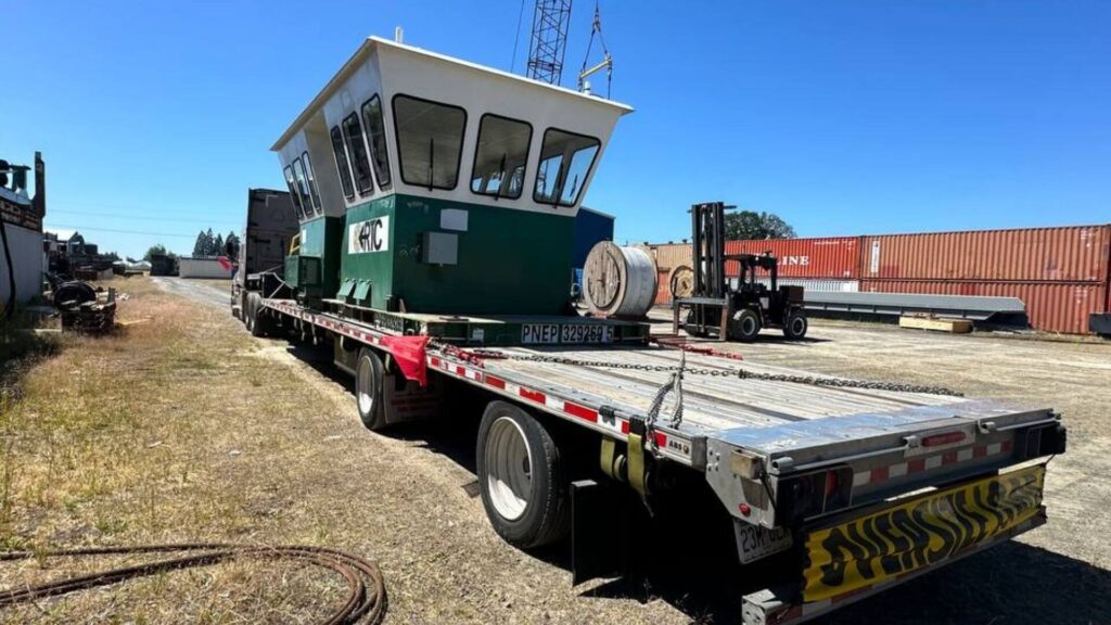 Marine construction equipment secured on a stepdeck trailer for freight transport by Abound Transport.