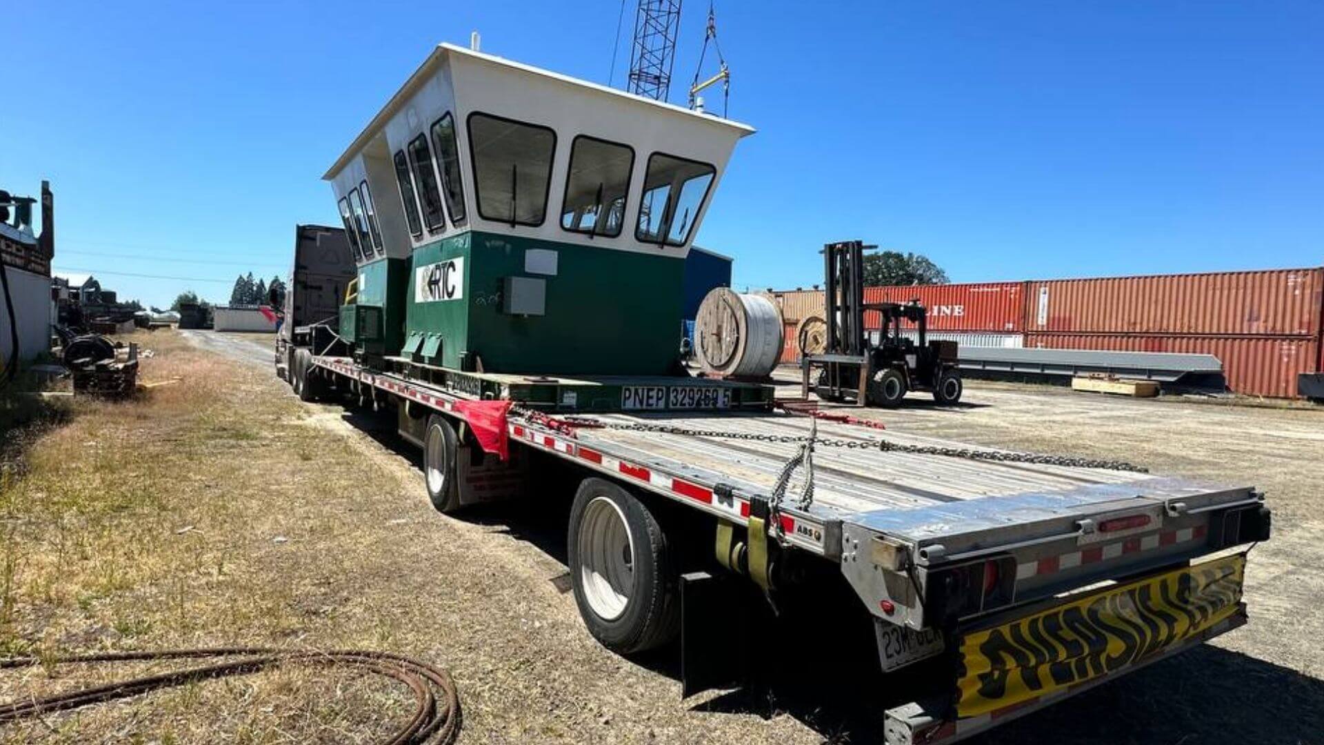 Marine construction equipment secured on a stepdeck trailer for freight transport by Abound Transport.