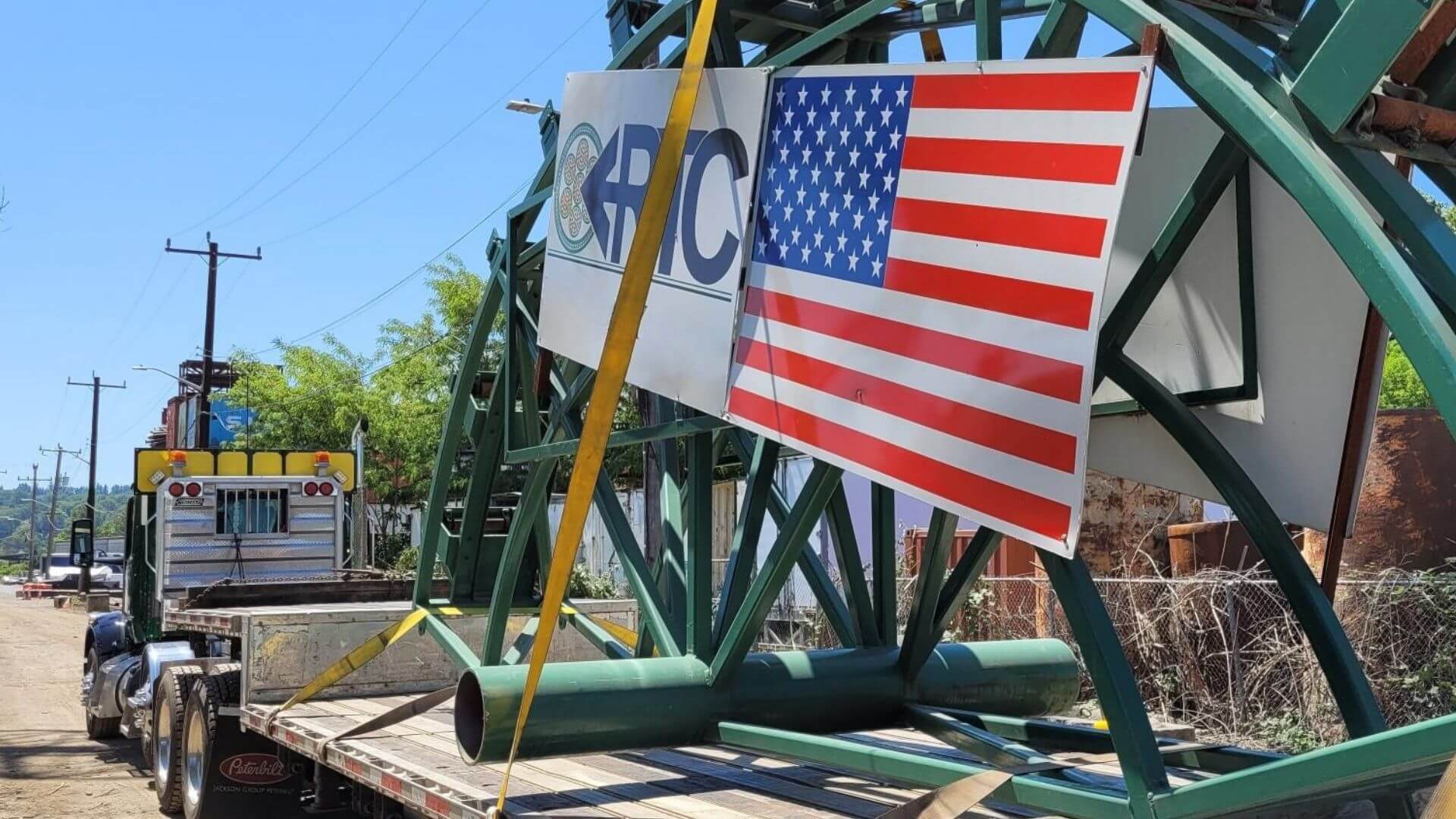 Cross Border Flag USA Canada Construction equipment secured on a flatbed trailer for nationwide freight shipping by Abound Transport.