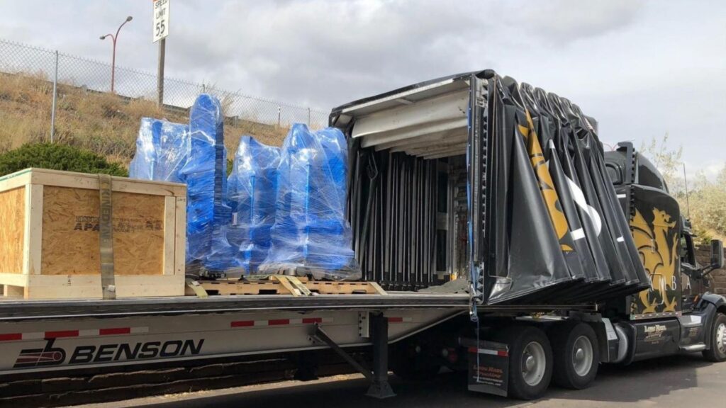 Conestoga curtainside trailer loaded with crated freight and blue barrels for PTL shipping Abound Transport