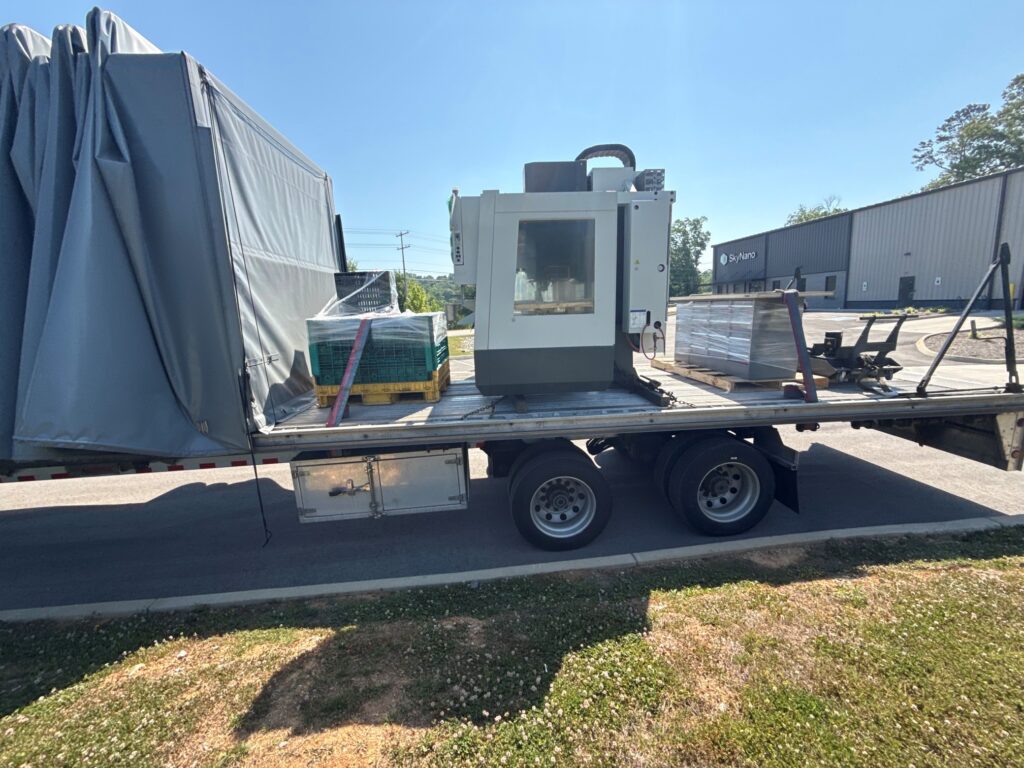 aas VF-2 CNC machining center loaded inside Conestoga flatbed trailer with accessory pallets for cross-country transport