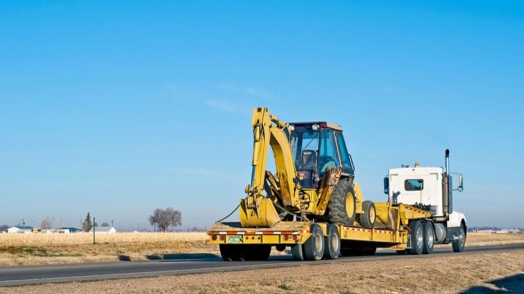 Backhoe loader secured on a lowboy trailer for heavy equipment transportation