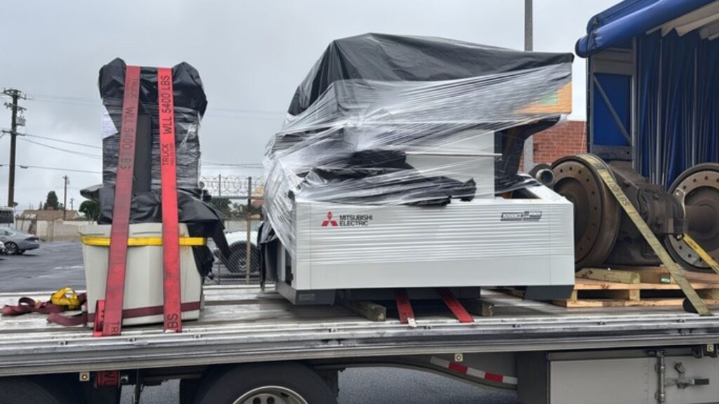 Mitsubishi industrial machinery secured on a flatbed trailer for transportation