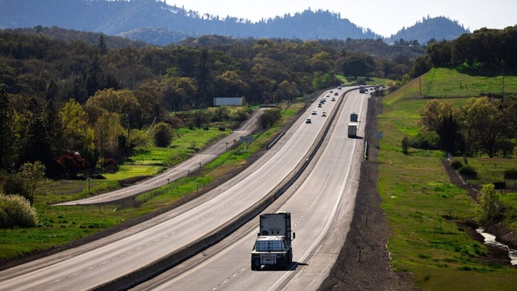 Flatbed truck traveling an Oregon highway through forested mountain terrain