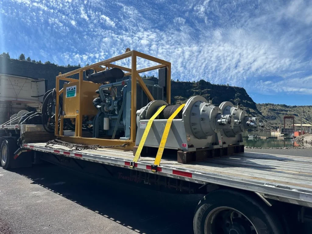 Heavy hydraulic marine winch and power unit strapped onto a flatbed trailer for transport
