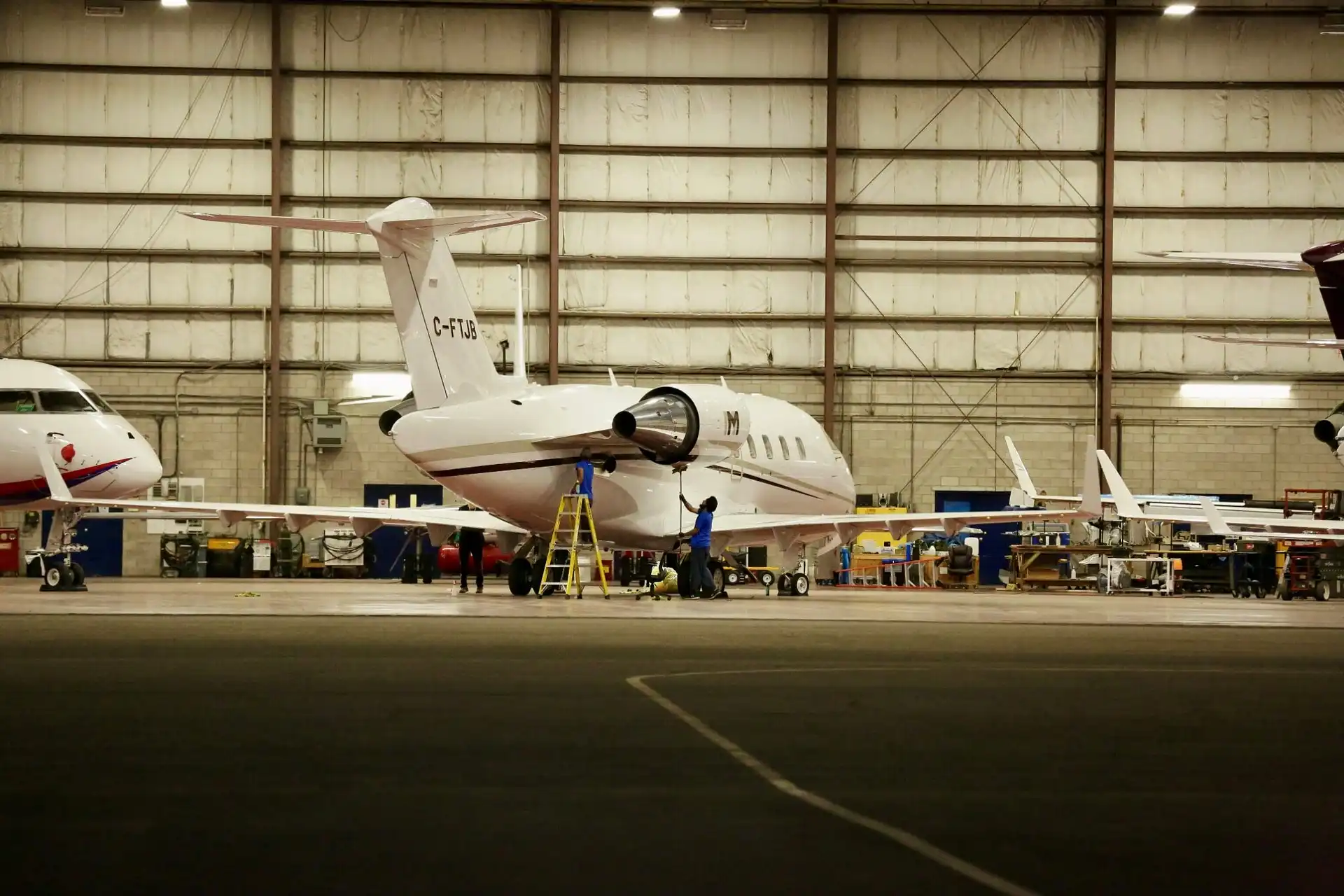 Private business jet undergoing maintenance and engine inspection inside an aircraft hangar for aviation parts logistics