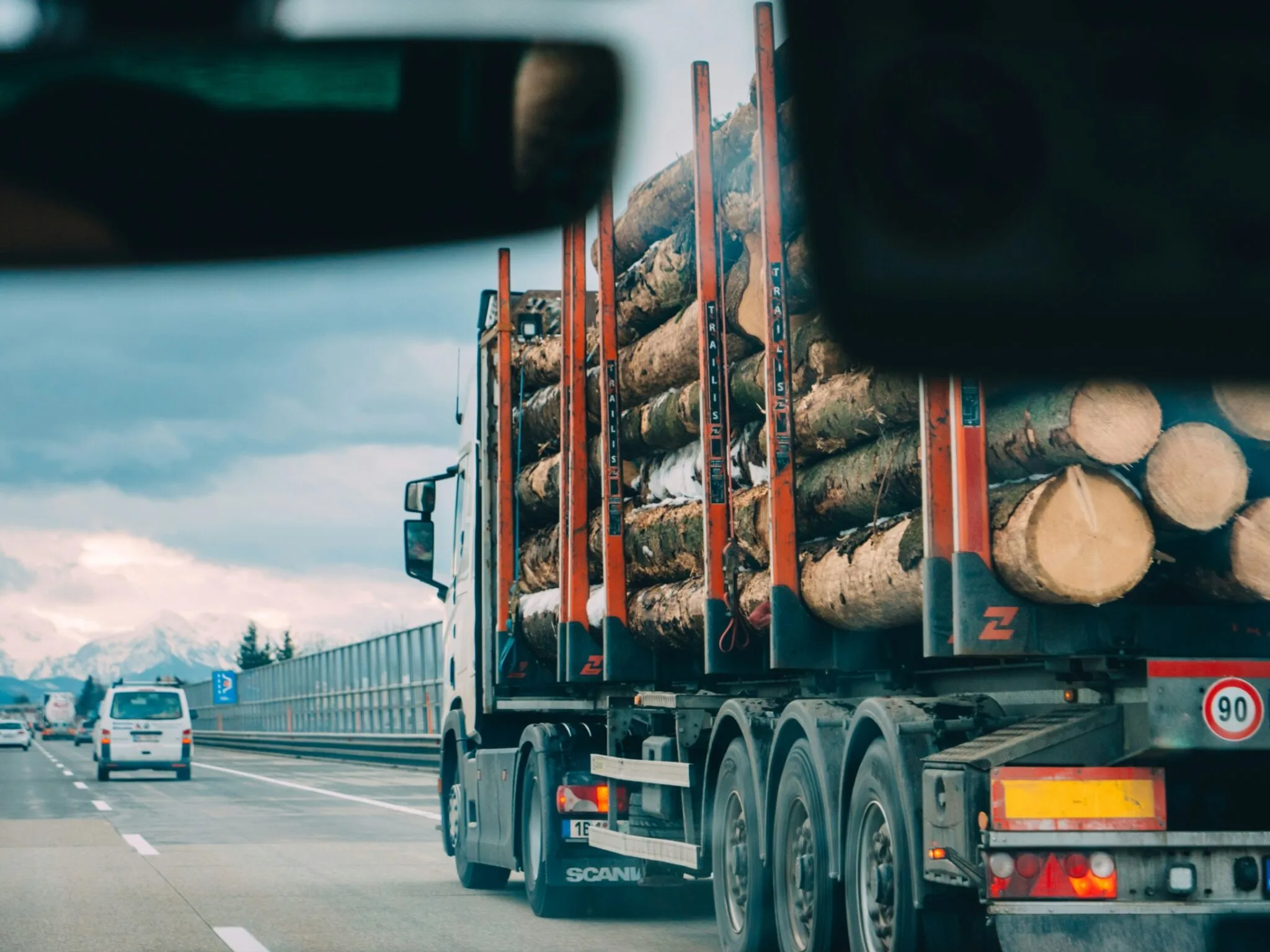 Commercial logging semi-truck hauling stacked raw timber logs on a highway for forestry and lumber freight transport