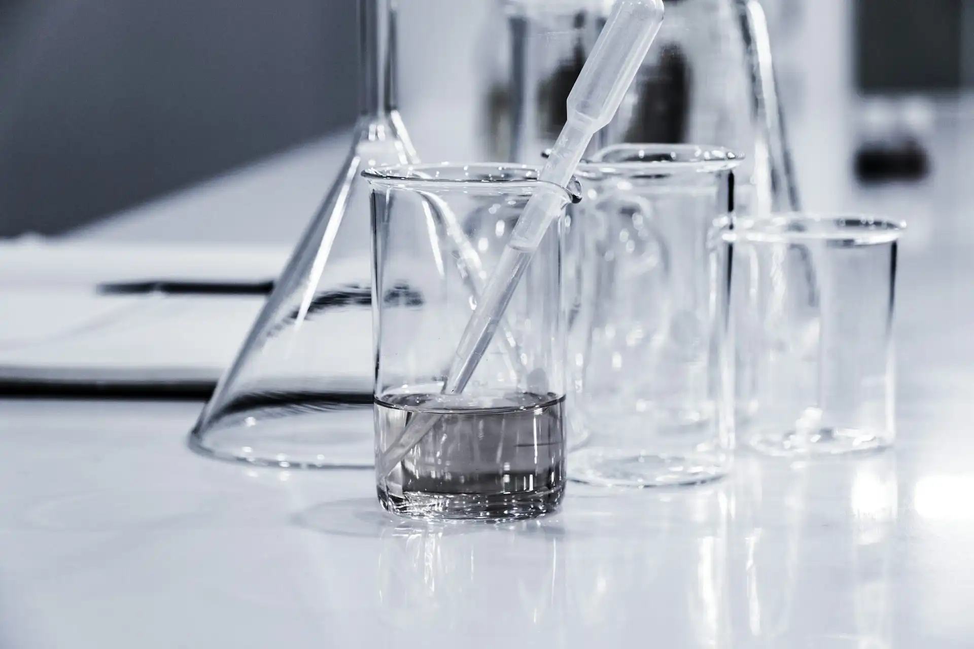 Laboratory glassware beakers, flasks, and pipette on workbench representing chemical manufacturing and pharmaceutical freight transport