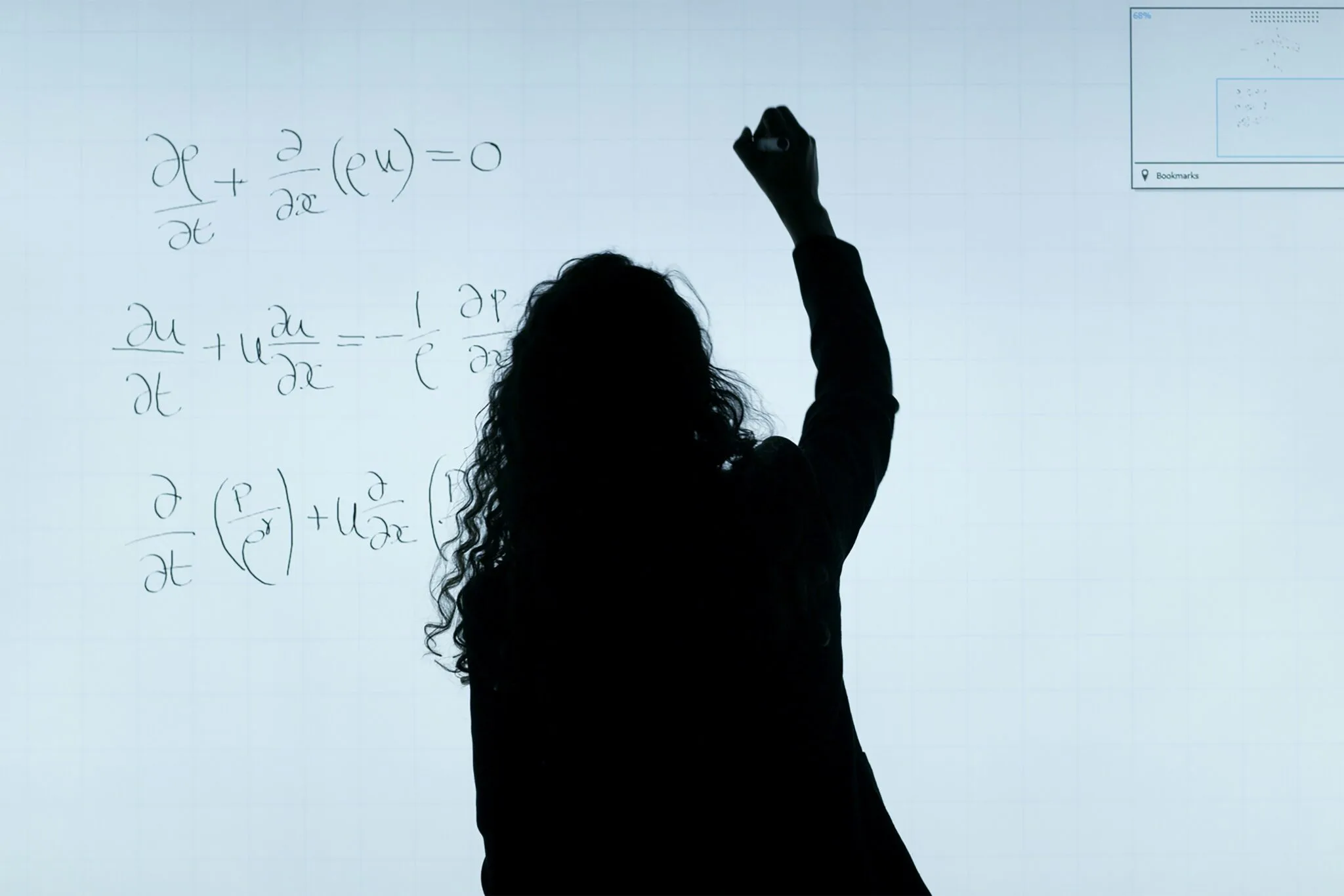 Silhouette of person solving advanced mathematical and physics equations on a whiteboard