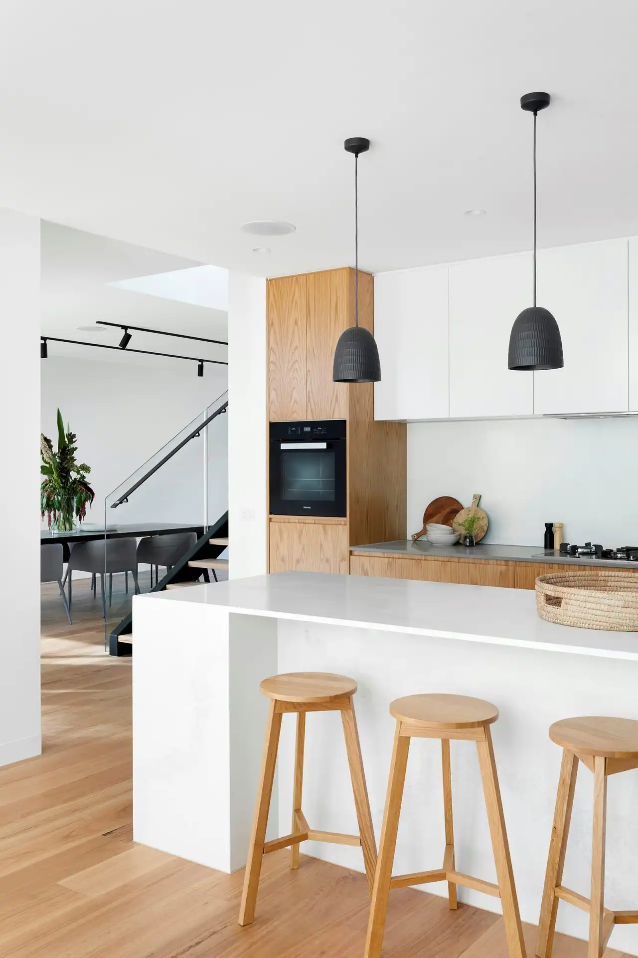Modern Scandinavian kitchen island with wooden barstools and pendant lighting representing residential building materials and furniture freight shipping