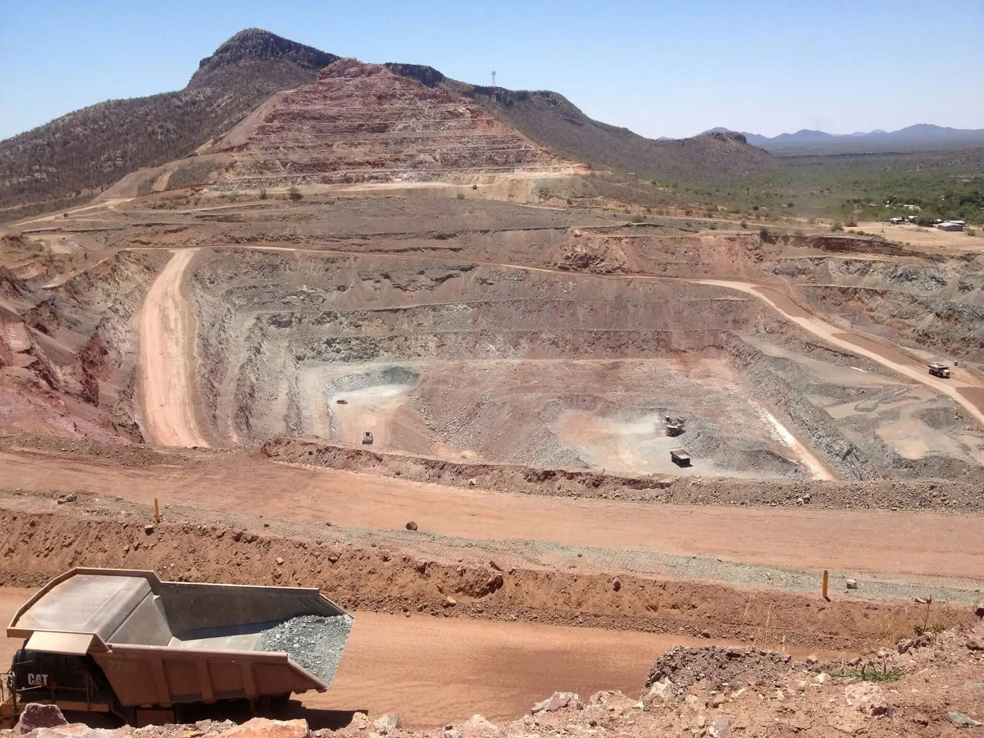 Large open-pit quarry mine with haul roads and heavy-duty CAT dump trucks representing mining logistics and heavy transport
