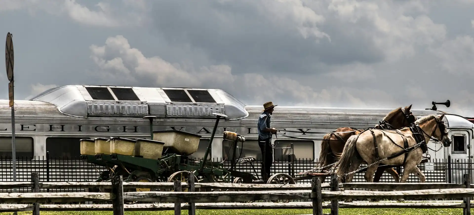 Farmer driving a horse-drawn agricultural planter past a vintage Lehigh Valley railroad car representing the evolution of freight transportation