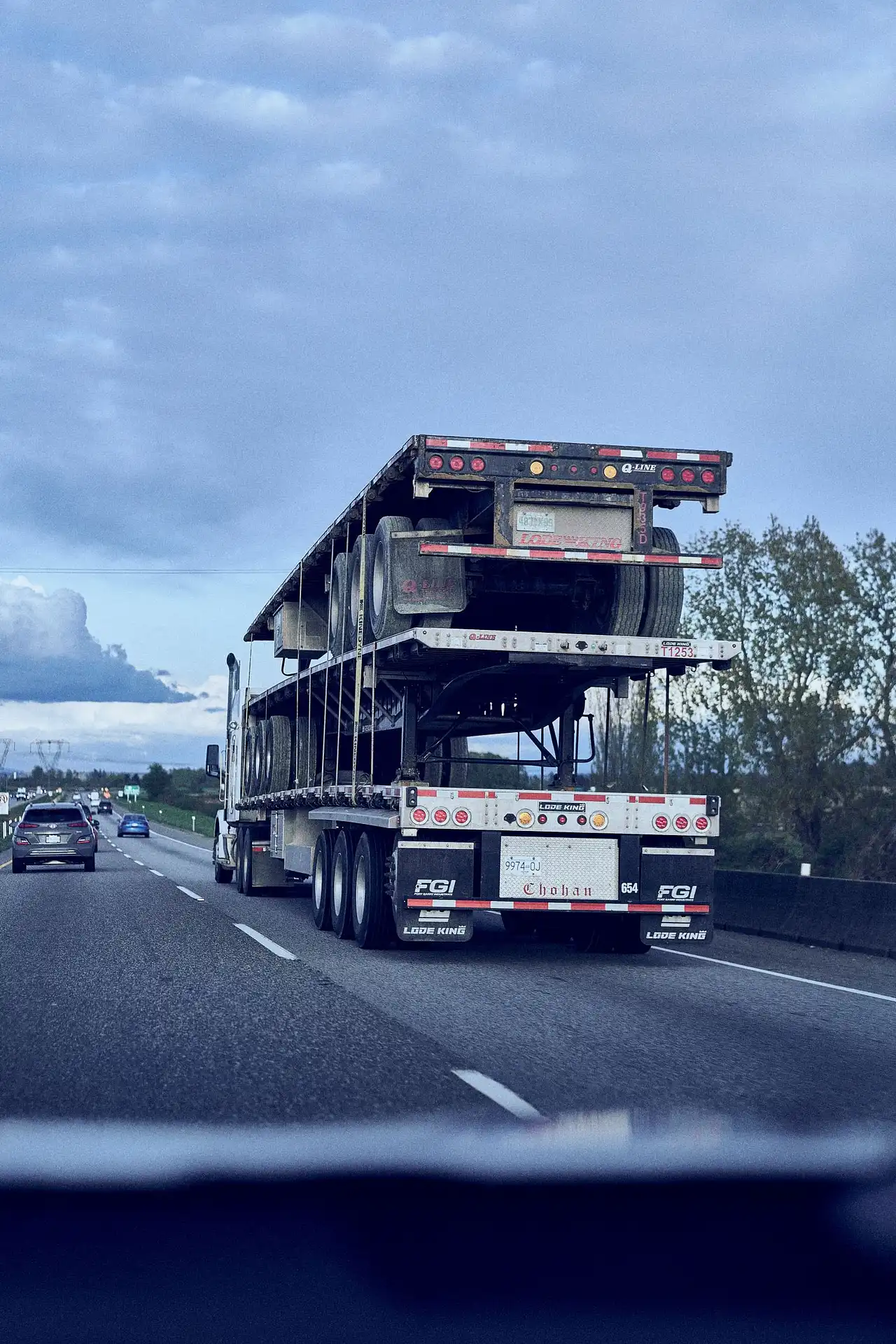Semi-truck piggybacking stacked flatbed trailers on highway for commercial fleet repositioning and heavy freight logistics