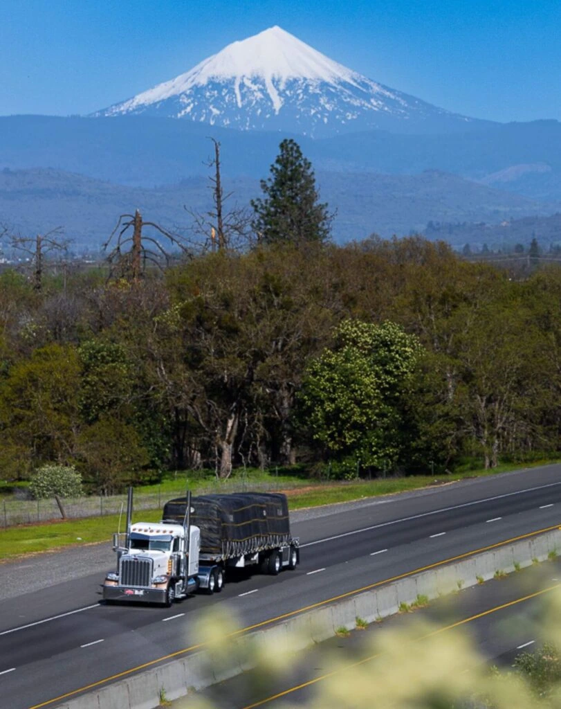 Abound Transport Group flatbed semi-truck hauling freight on highway with scenic mountain view