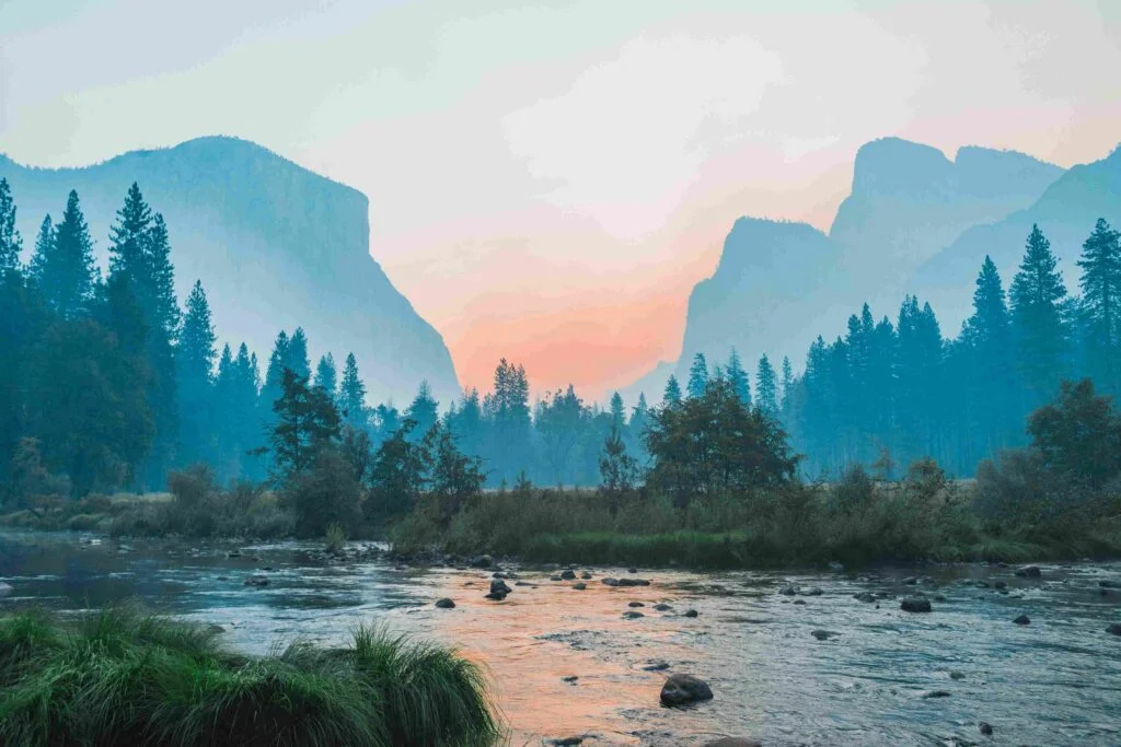 Scenic sunrise over the Merced River with pine trees and granite peaks in Yosemite Valley
