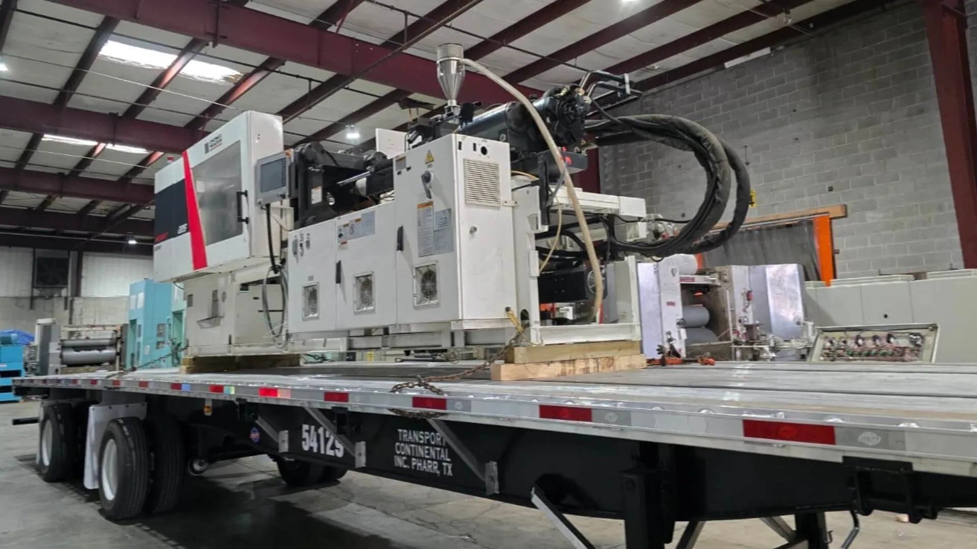 Cincinnati Milacron MTS-225 injection molding machine loaded for cross-border transport to Mexico