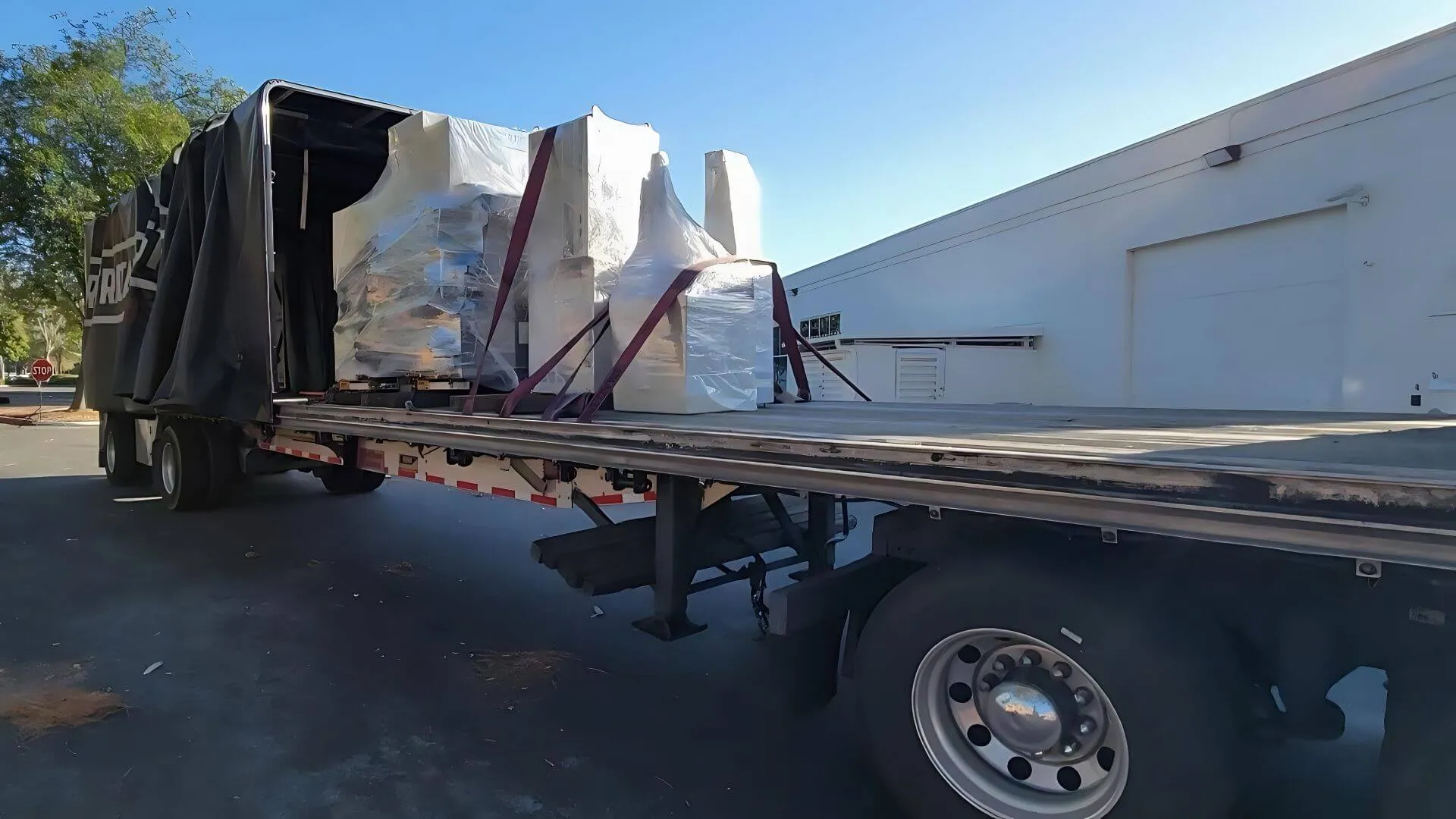 Conestoga curtain side flatbed trailer loaded with palletized stretch-wrapped freight and cargo straps