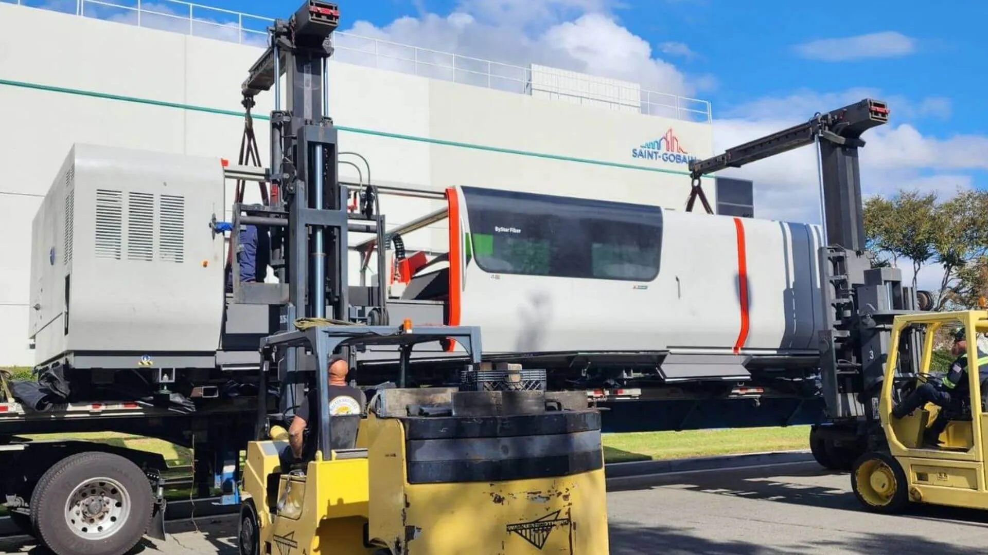 CNC machine being forklifted off a flatbed trailer by Abound Transport