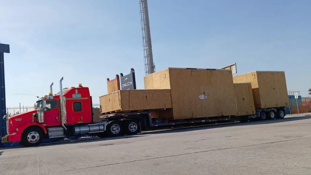 crated cnc machinery loaded on a double drop trailer for long haul transport to port driver has twic card