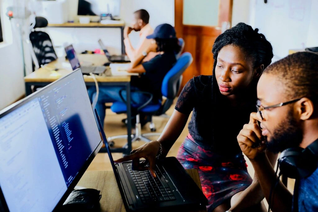 Logistics dispatch team analyzing freight tracking data and software on computer monitors in an office setting