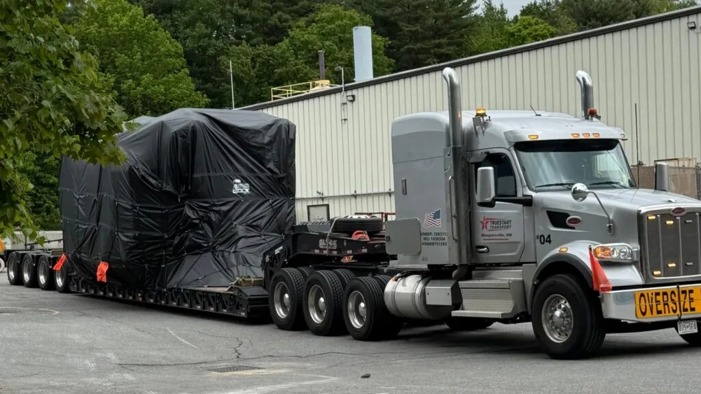 Industrial equipment tarped on a 7 axle rgn trailer for heavy haul transport.