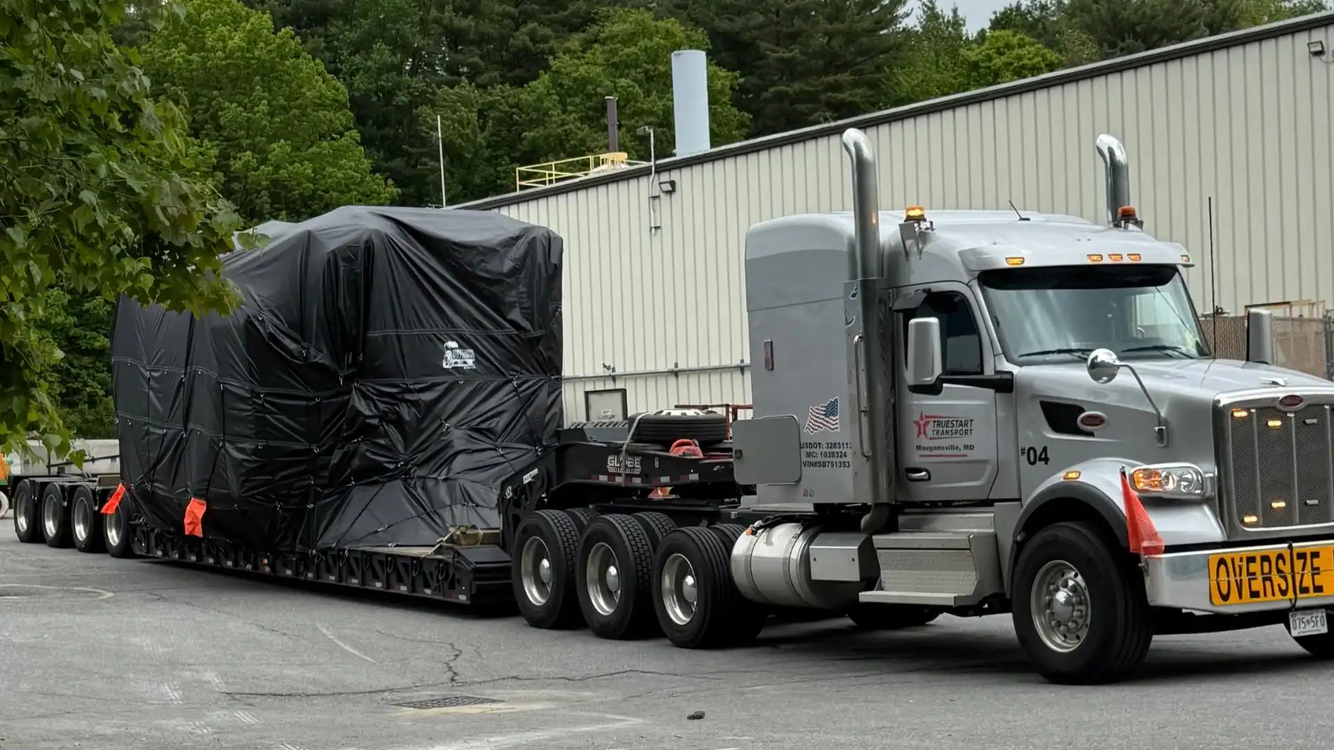 Industrial equipment tarped on a 7 axle rgn trailer for heavy haul transport.