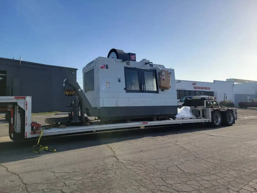 Heavy industrial CNC machinery loaded on lowboy trailer for freight transport