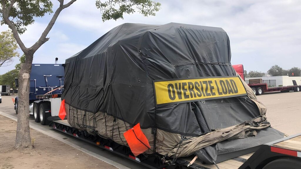 Double drop trailer hauling cnc machinery fully tarped and ready to leave seattle, wa for a long haul cross country move for Abound Transport Group
