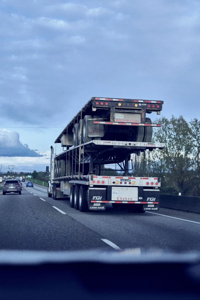 Semi-truck hauling stacked empty flatbed trailers on highway for equipment repositioning
