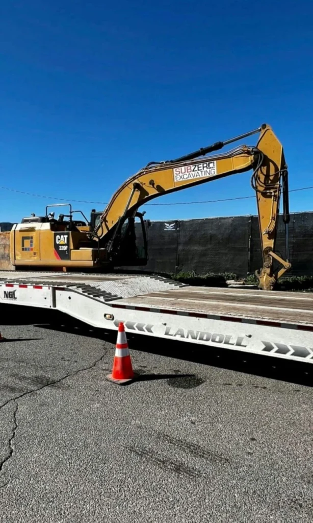 Yellow Caterpillar CAT 320F excavator loaded on a Landoll lowboy trailer for heavy haul transport