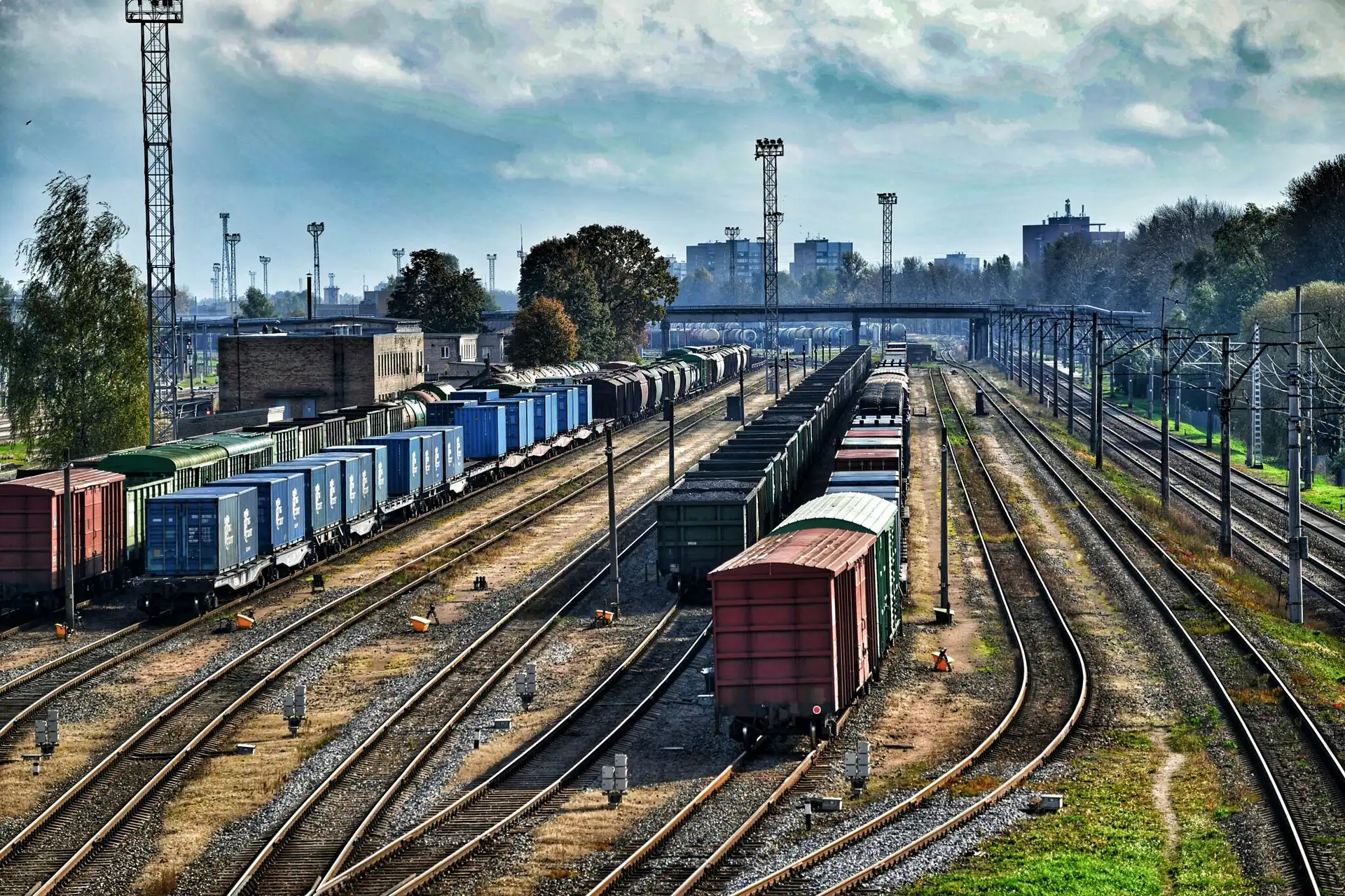 Large industrial rail classification yard with parallel tracks and rows of intermodal freight cars, shipping containers, and boxcars