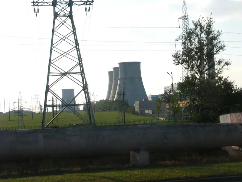 High-voltage power transmission towers and industrial cooling towers at an energy plant facility