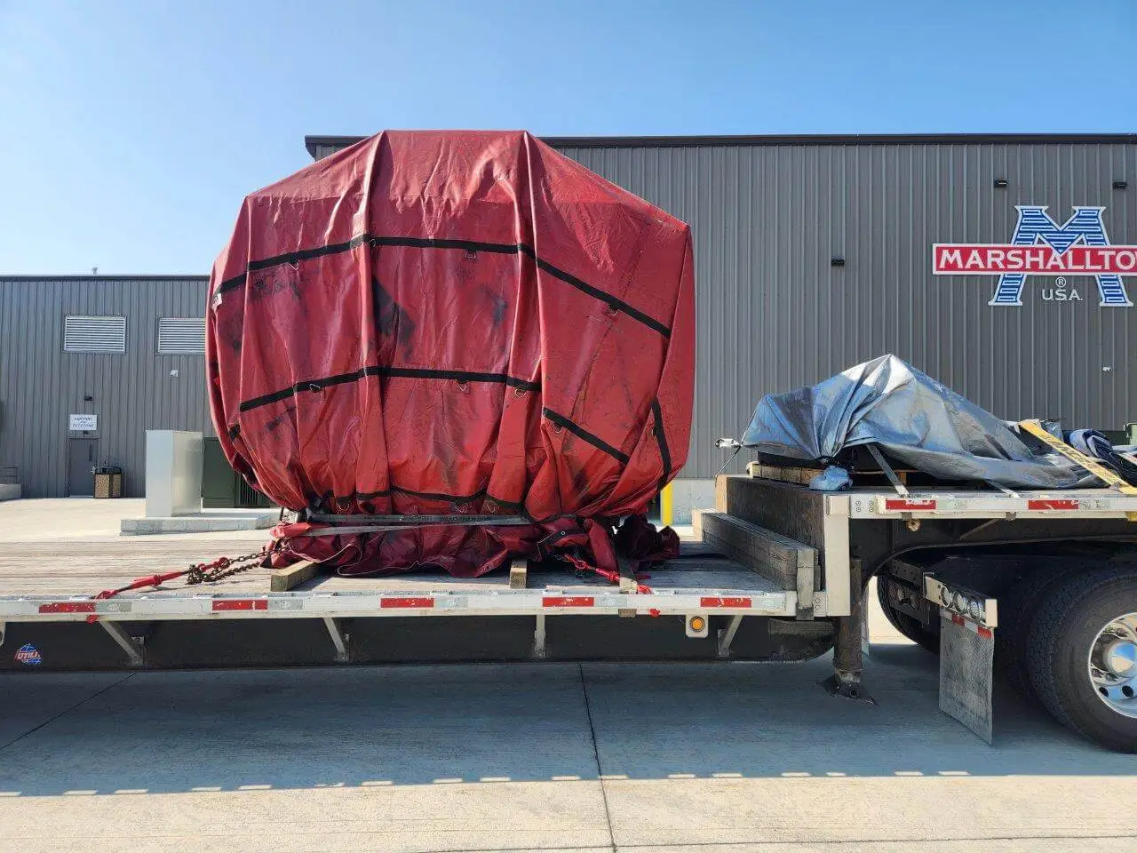 Red tarped cnc machine freight on flatbed partial truckload shipment by Abound Transport