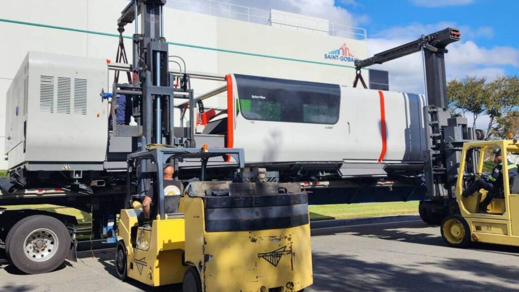 Machinery rigger preparing loading laster on to a flatbed stretch trailer at a customers facility