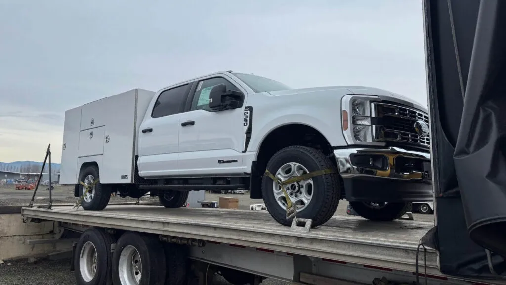 Highway Products service truck secured on Conestoga flatbed for enclosed vehicle transport