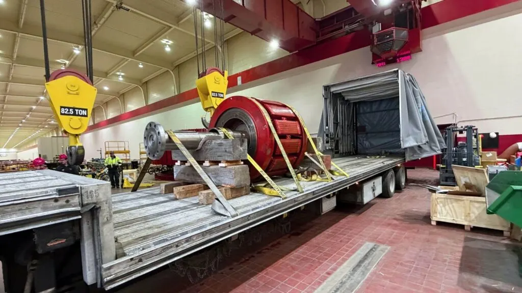 Retractable Conestoga step deck trailer loaded with heavy industrial turbine machinery for USA-Canada cross-border freight transport