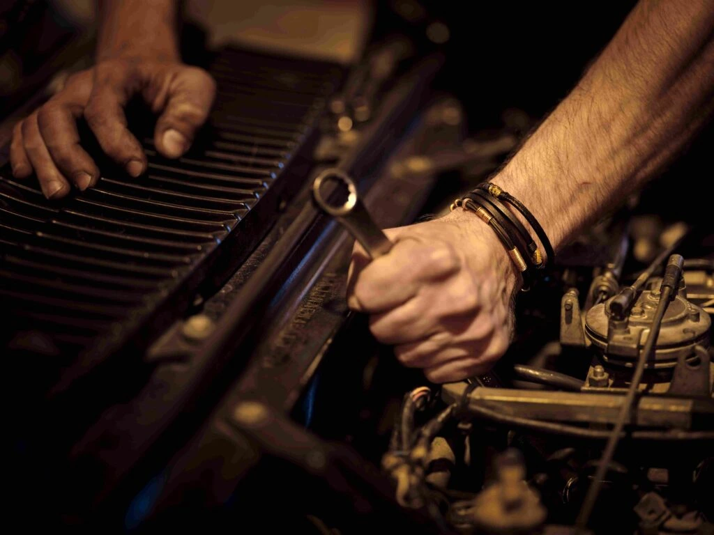 Mechanic hands using a wrench to repair vehicle engine block during commercial fleet maintenance and diesel truck servicing